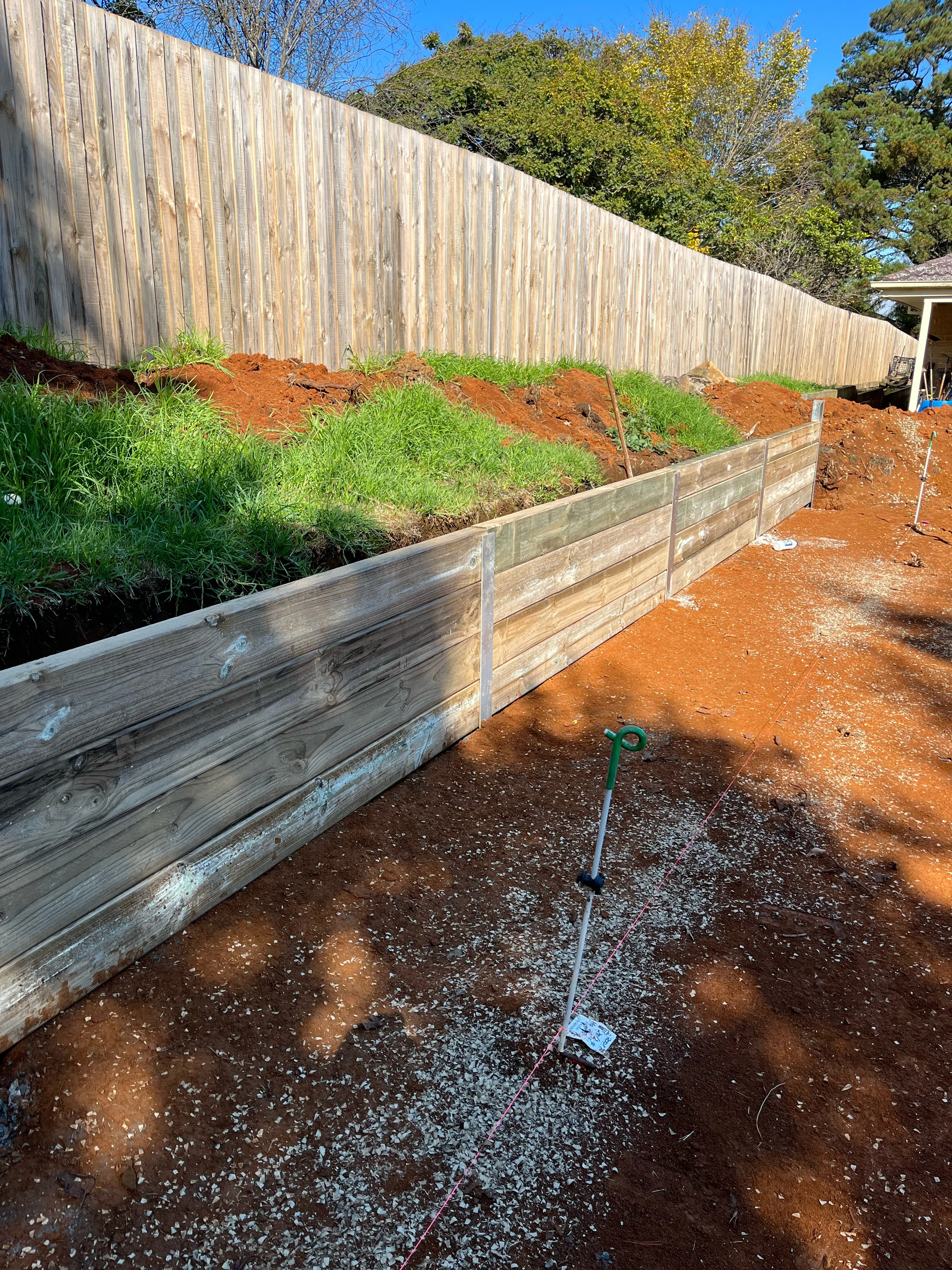 Sleeper retaining wall on steel posts with gravel drainage being placed at the toe.