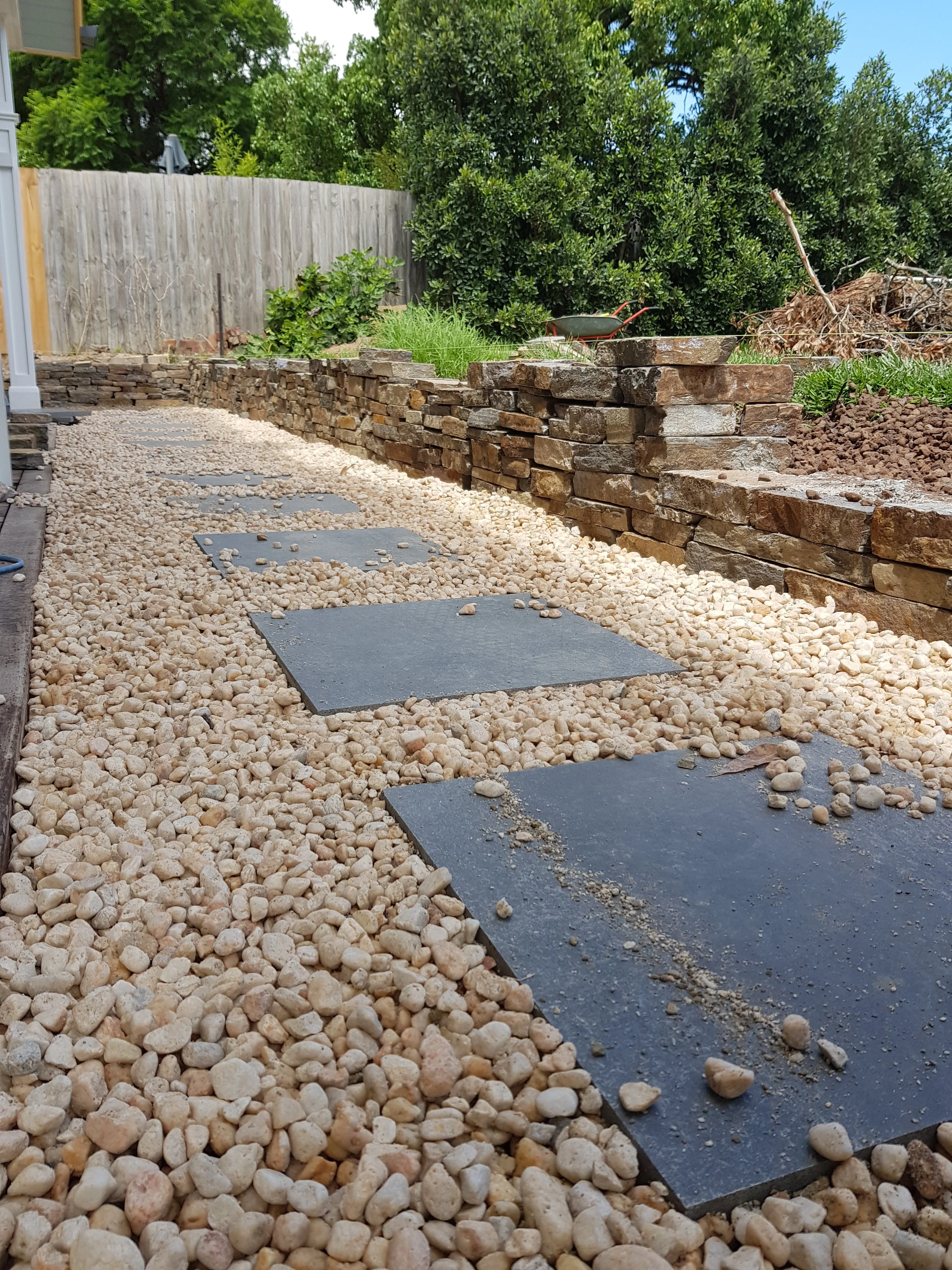 Cream river-pebble path with large bluestone stepping stones running beside a dry stone wall.