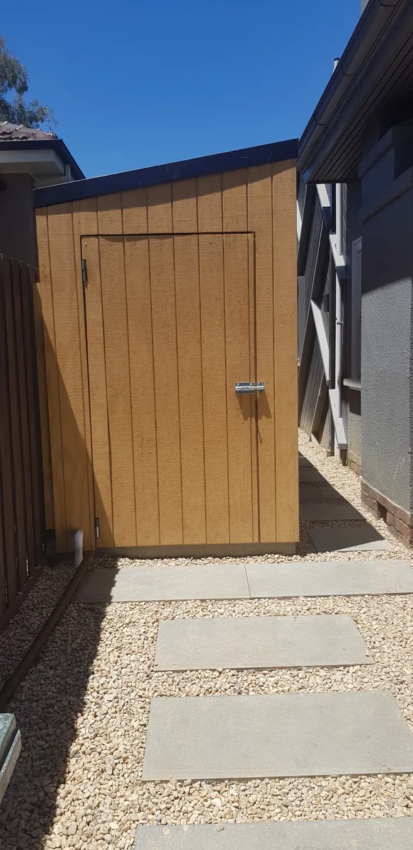 Gravel side path with stepping pavers leading to a timber-clad shed