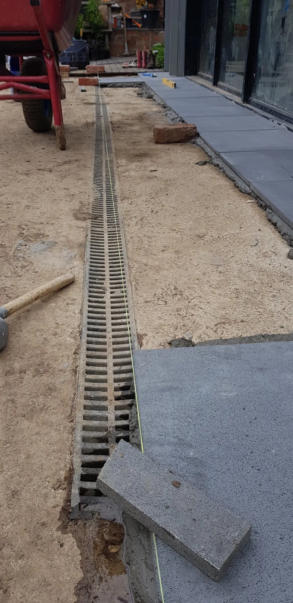 Drain channel set in a sand base with the first large-format pavers laid