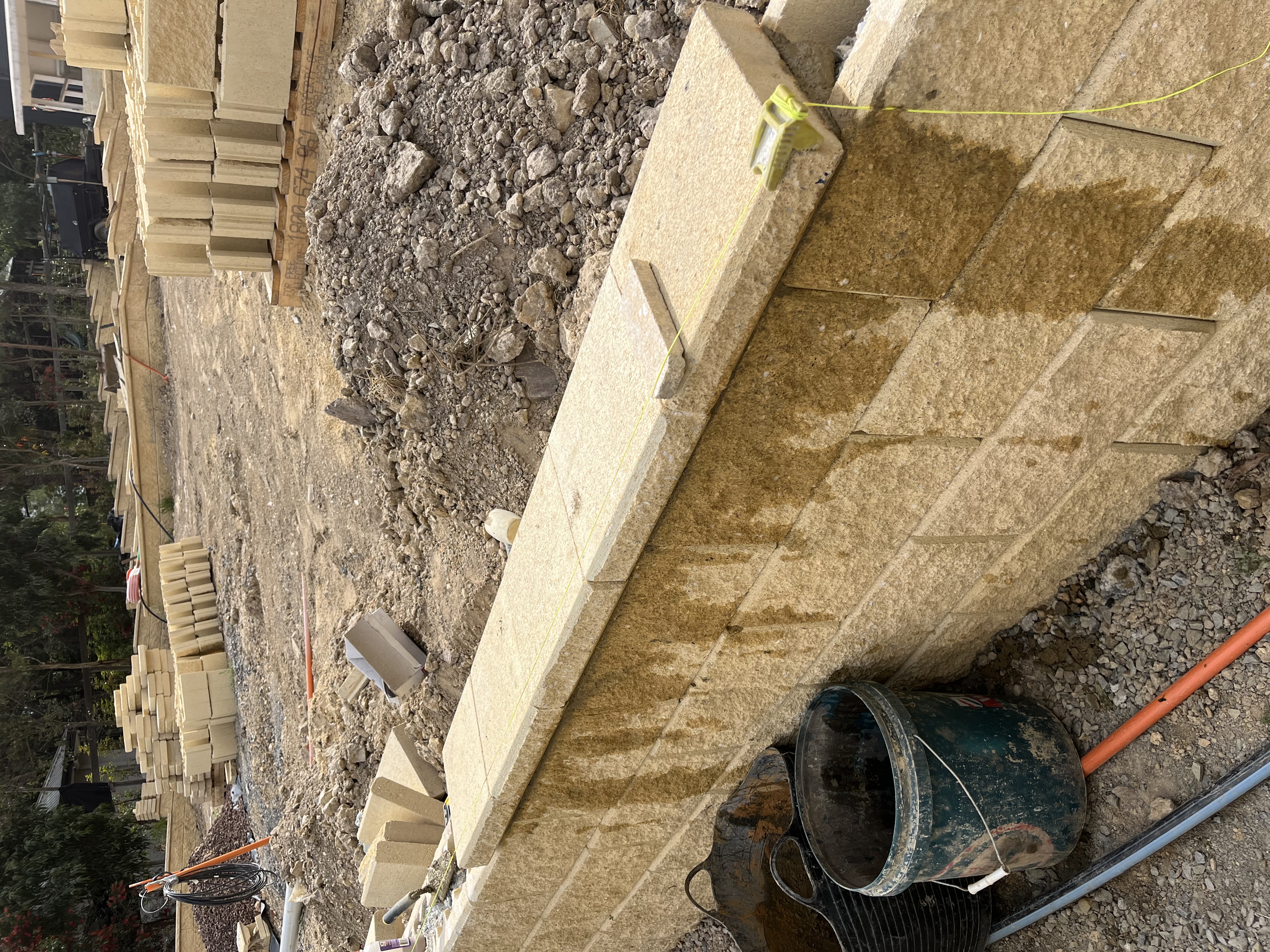 Concrete block retaining wall being constructed with materials nearby